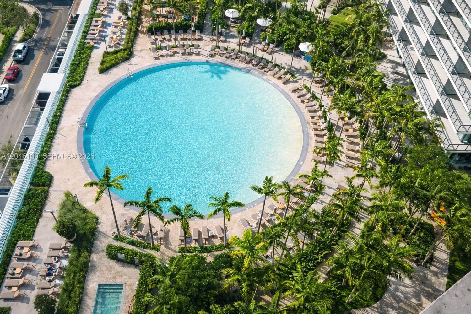 An aerial view shows a large circular swimming pool surrounded by palm trees and lounge chairs — 650 NE 32nd St # 2005, Miami FL 33137, MIAMI, FL