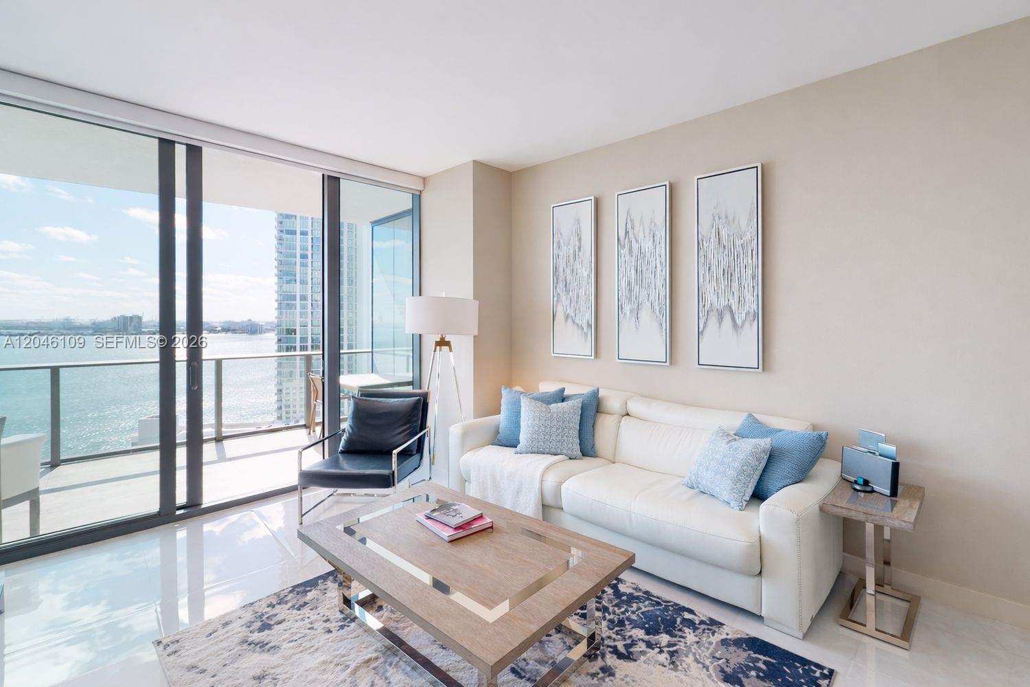 A living room features a white sofa, coffee table, and balcony with a water view — 650 NE 32nd St # 2005, Miami FL 33137, MIAMI, FL