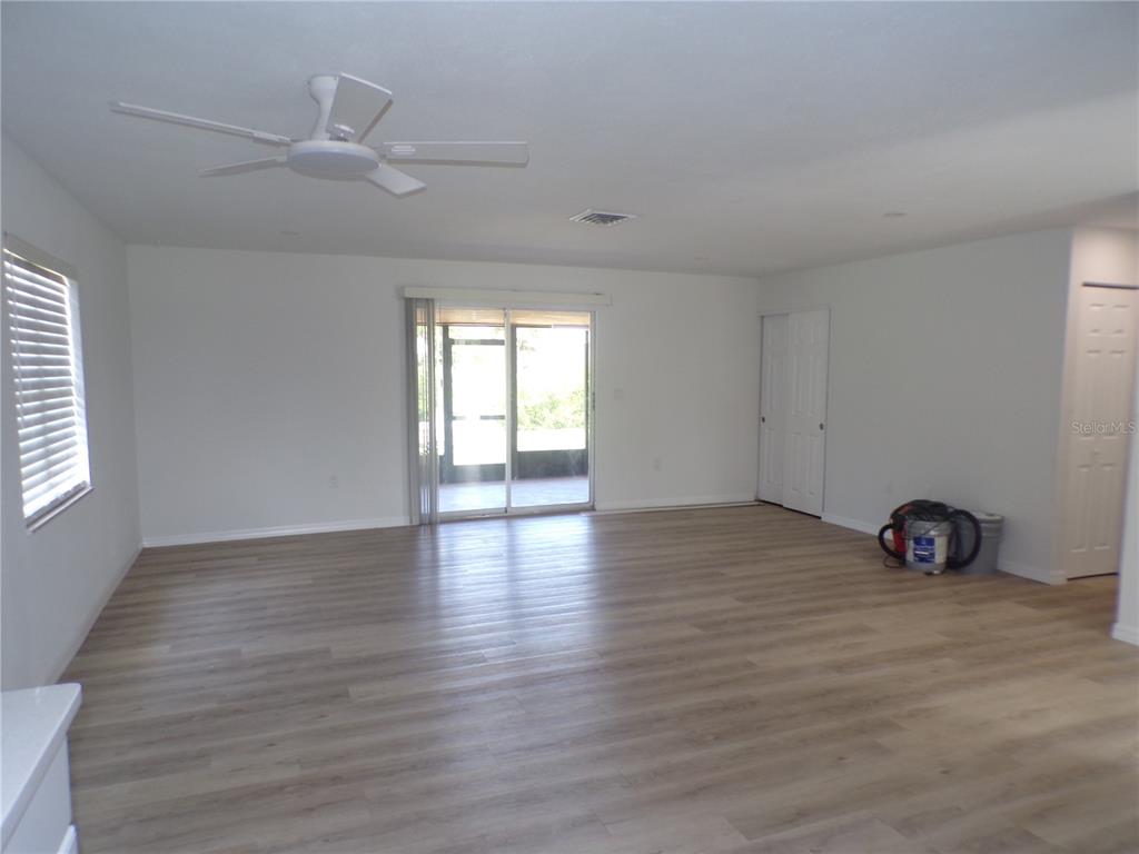 An empty room features light wood-look flooring, white walls, recessed lighting, and a sliding door — 421 ORCHID DRIVE, PUNTA GORDA, FL