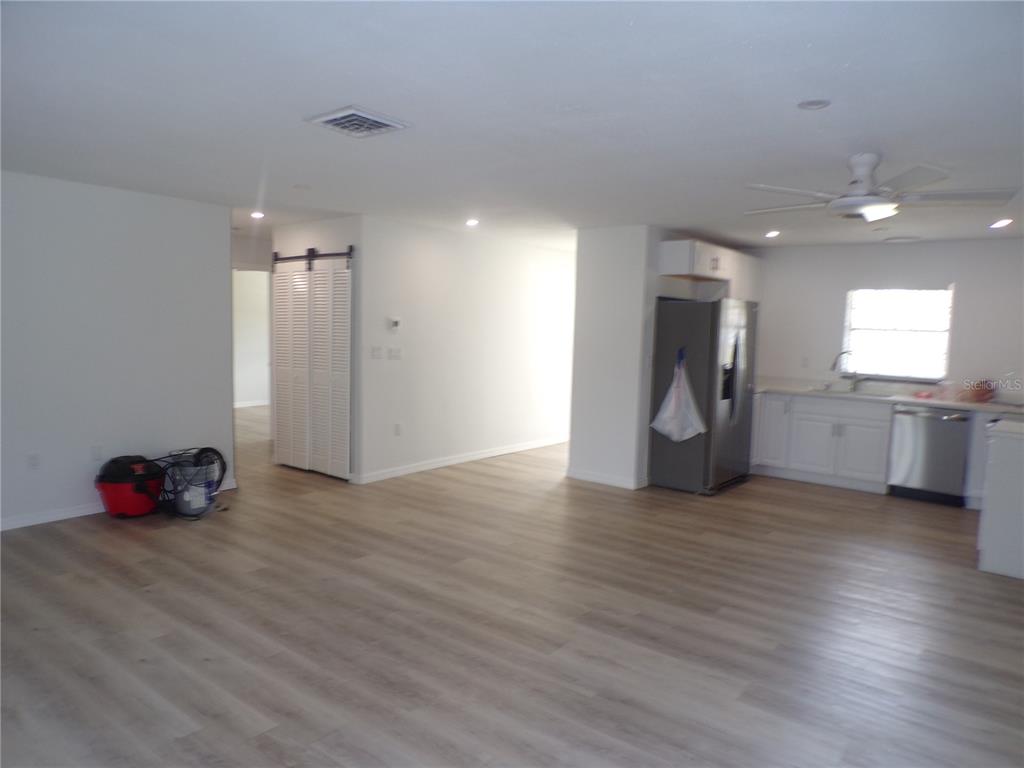An open-concept living area features light wood-look flooring, white walls, recessed lighting, and a kitchen — 421 ORCHID DRIVE, PUNTA GORDA, FL