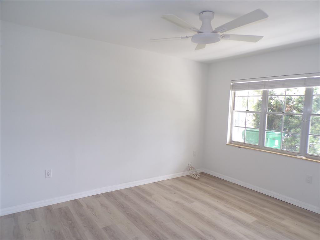A spacious room features light wood-look flooring, white walls, a ceiling fan, and sliding doors — 421 ORCHID DRIVE, PUNTA GORDA, FL
