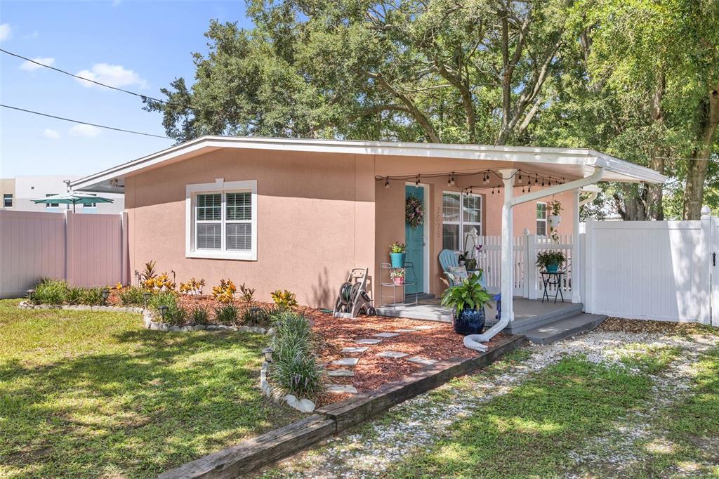 A single-story pink house with a covered porch, white fence, and landscaped front yard — 3626 GRANT BOULEVARD, ORLANDO, FL