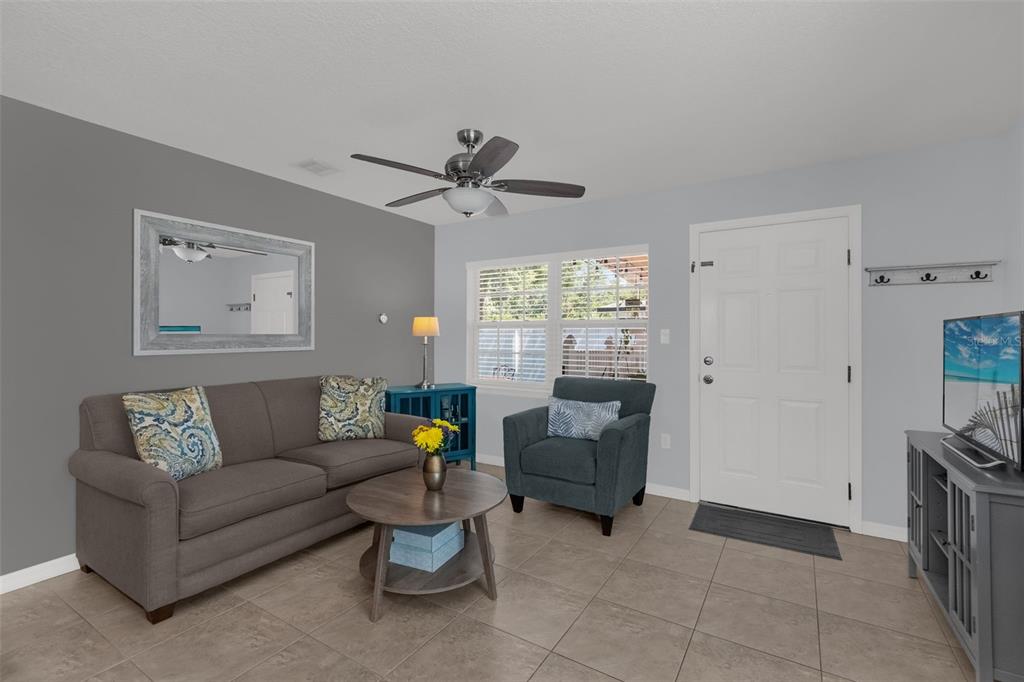 A living room features a grey sofa, a blue armchair, and a television on a stand — 3626 GRANT BOULEVARD, ORLANDO, FL