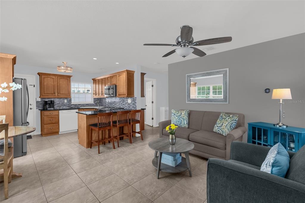 An open-concept kitchen and living room featuring wood cabinets, tile flooring, and a gray wall — 3626 GRANT BOULEVARD, ORLANDO, FL