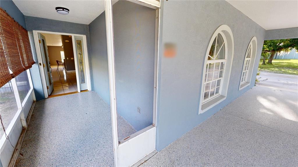 A covered porch with a speckled floor, screen door, and arched windows on a blue wall — 22262 SEYBURN TERRACE, PORT CHARLOTTE, FL