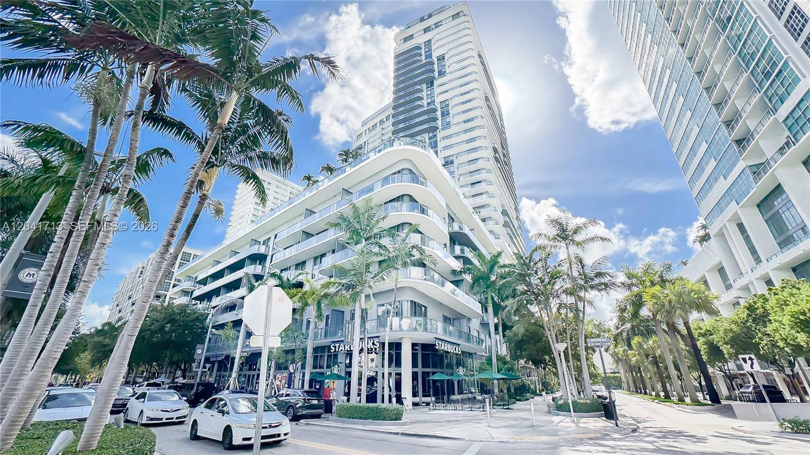 A low-angle exterior view of a modern multi-story apartment building with a ground-level Starbucks — 121 NE 34th St # 814, Miami FL 33137, MIAMI, FL