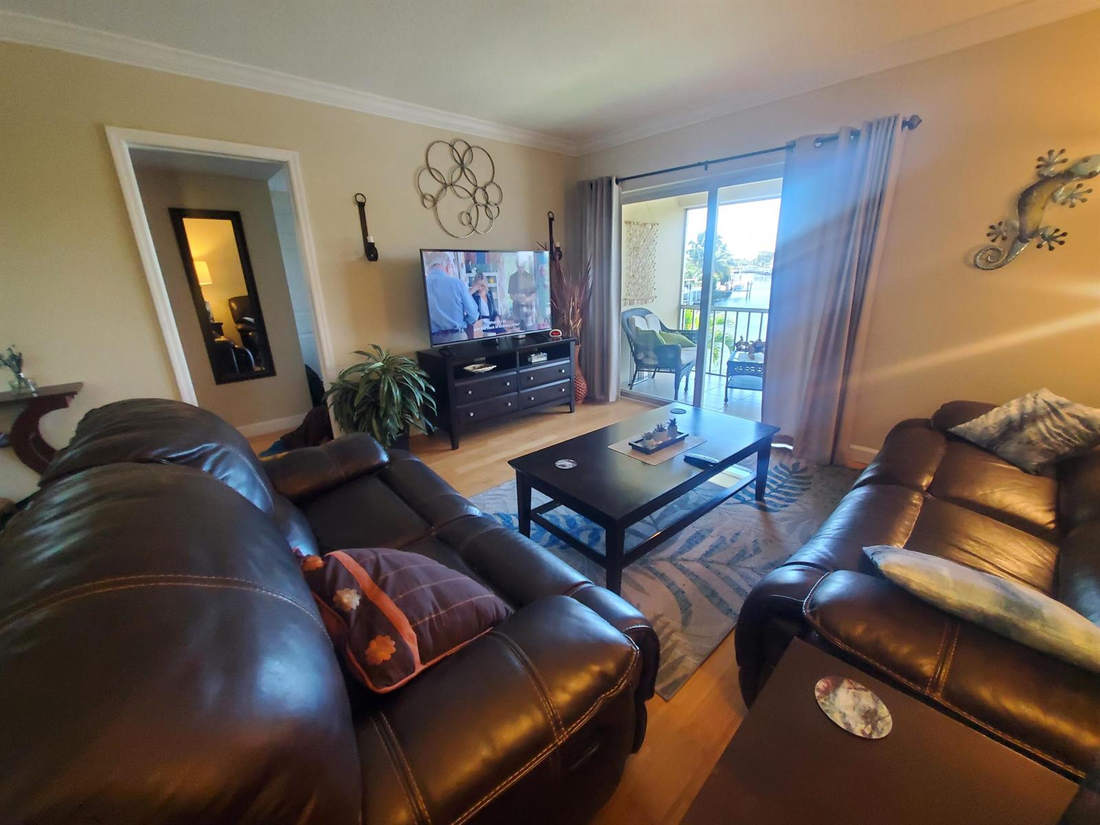 A living room features dark leather sofas, a coffee table, and a sliding door to a balcony — 912 Pine Drive # 211, Pompano Beach FL 33060, POMPANO BEACH, FL