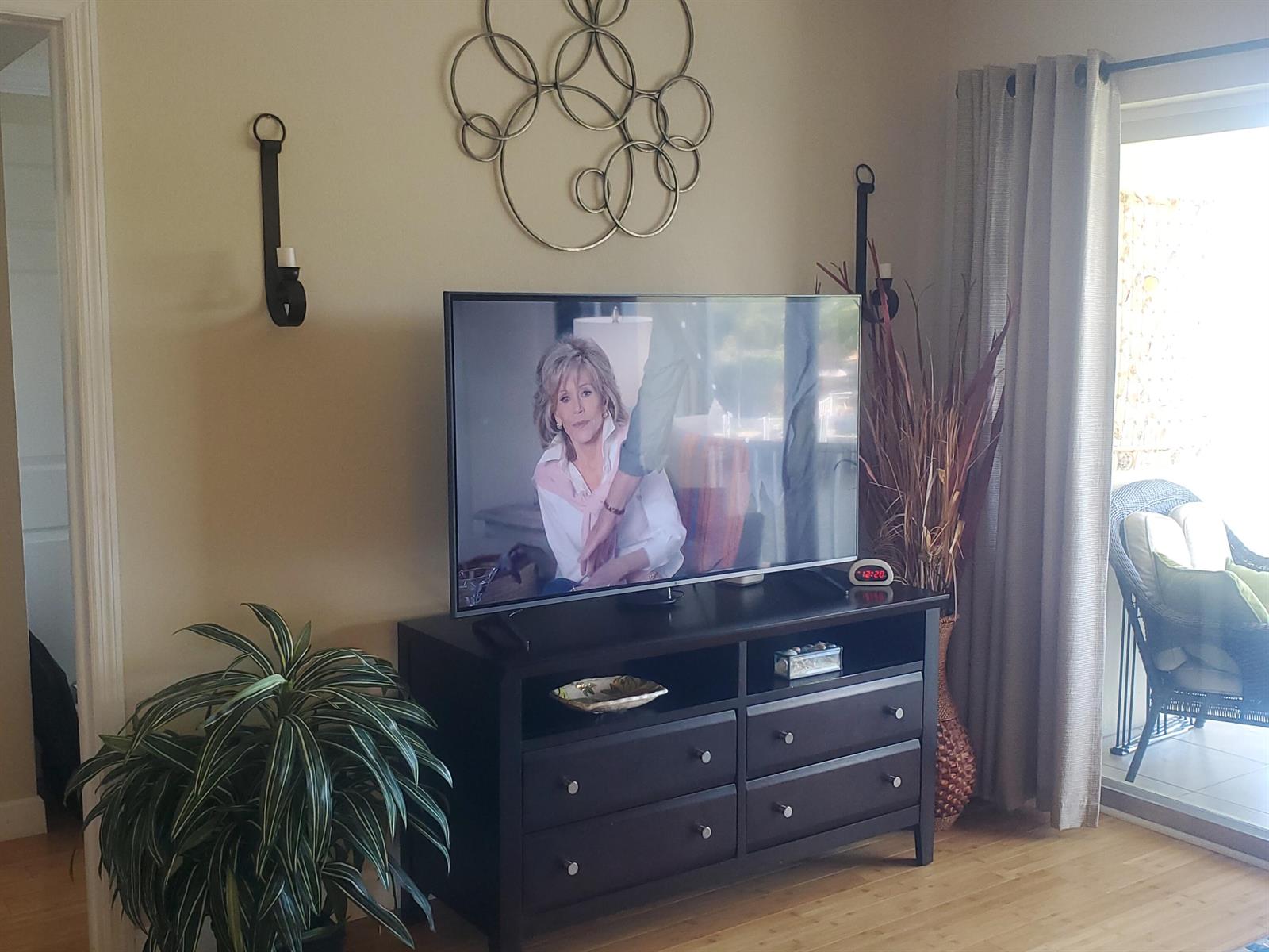 A living room features a dark wood media console, a television, wall sconces, and a plant — 912 Pine Drive # 211, Pompano Beach FL 33060, POMPANO BEACH, FL