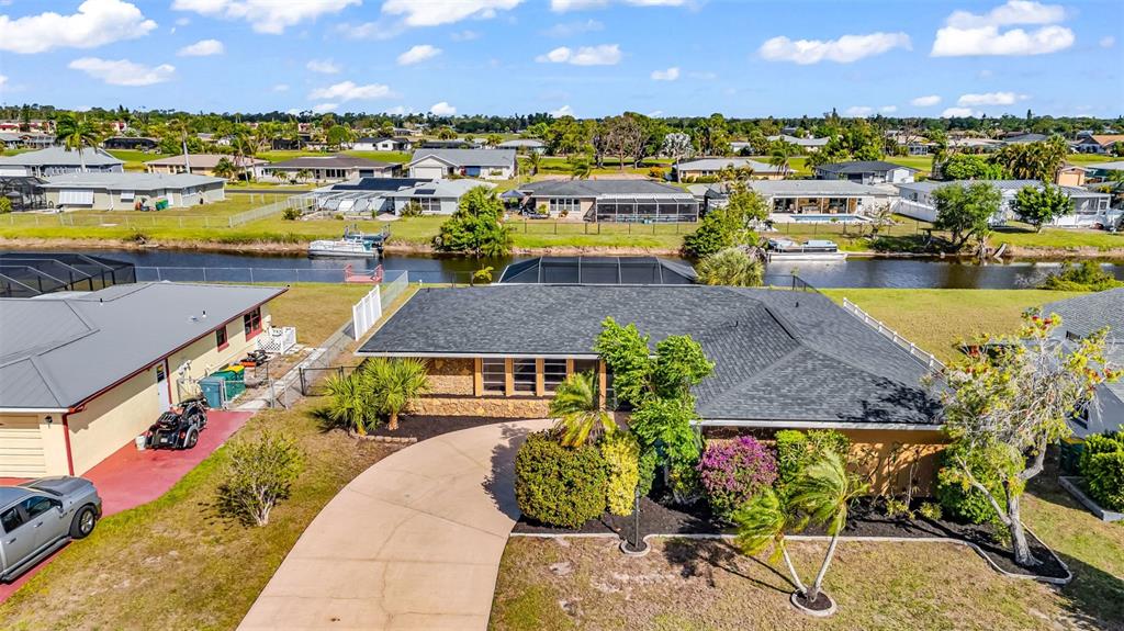 An aerial view shows a single-story house with a dark roof, driveway, and canal frontage — 18 ANNAPOLIS LANE, ROTONDA WEST, FL