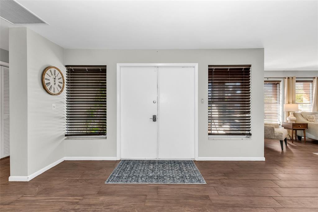 A foyer features double white doors, dark wood-look tile flooring, and two windows with blinds — 18 ANNAPOLIS LANE, ROTONDA WEST, FL