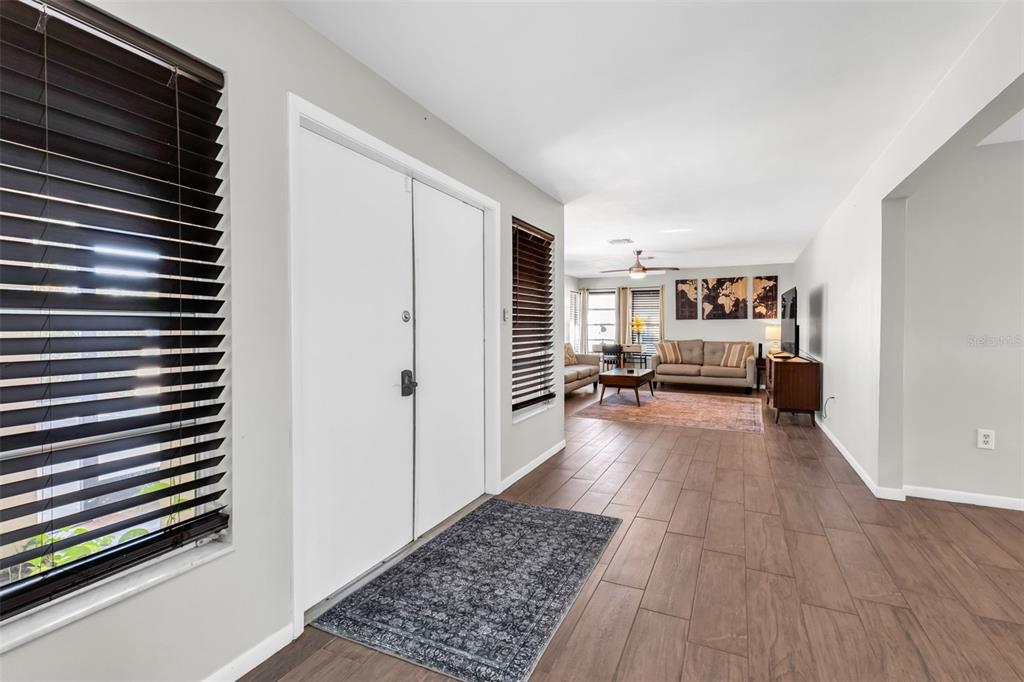 An entryway with tile flooring leads into a living room featuring a sofa and area rug — 18 ANNAPOLIS LANE, ROTONDA WEST, FL