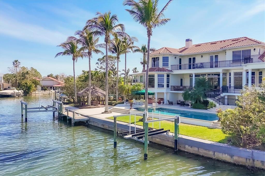 A large waterfront house features a swimming pool, boat dock, and palm trees on the lawn — 1137 N LAKE SHORE DRIVE, SARASOTA, FL