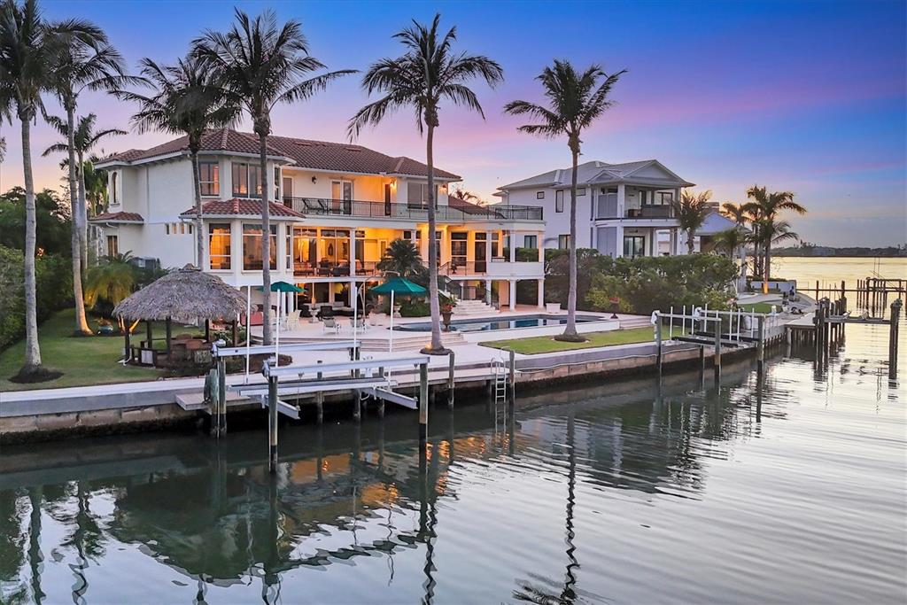 A multi-story waterfront house with a pool, boat dock, and palm trees at sunset — 1137 N LAKE SHORE DRIVE, SARASOTA, FL