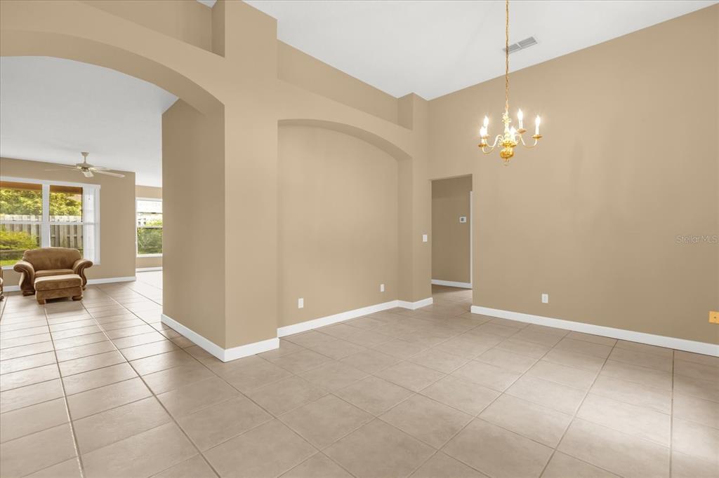 An empty dining room with beige walls, tile flooring, and a decorative chandelier — 5653 MAGNOLIA BLOOM TERRACE, OVIEDO, FL