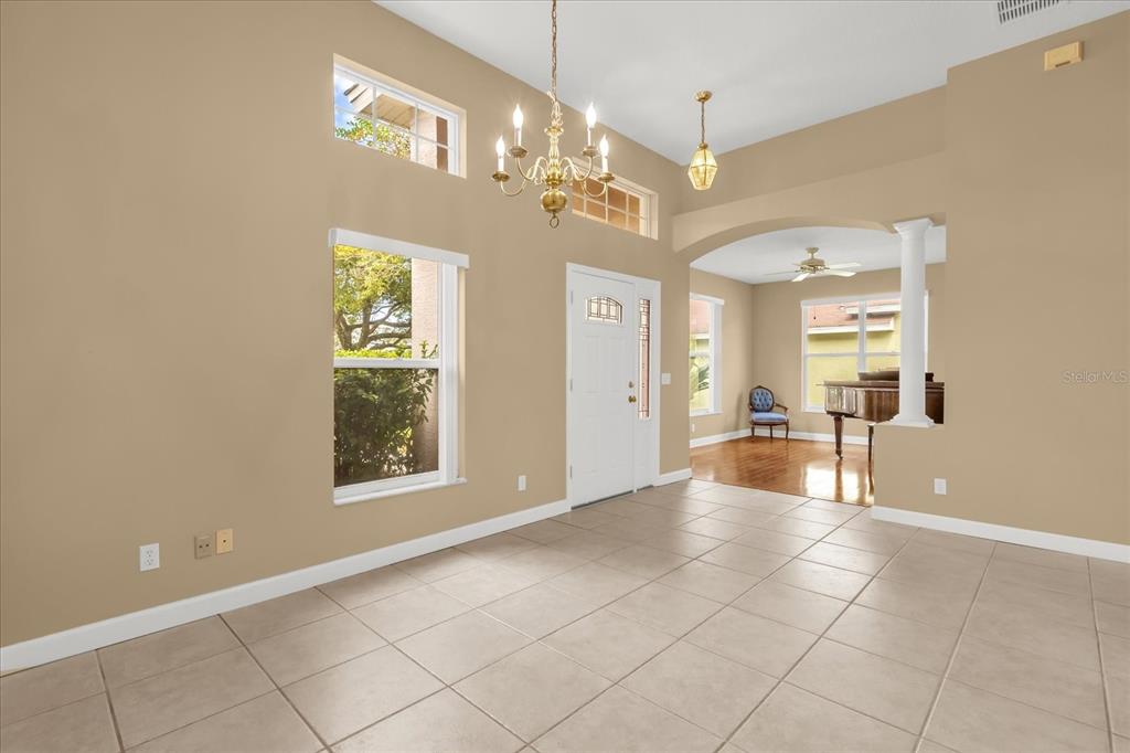 A bright foyer with tile flooring, a chandelier, and an arched entryway to a room — 5653 MAGNOLIA BLOOM TERRACE, OVIEDO, FL