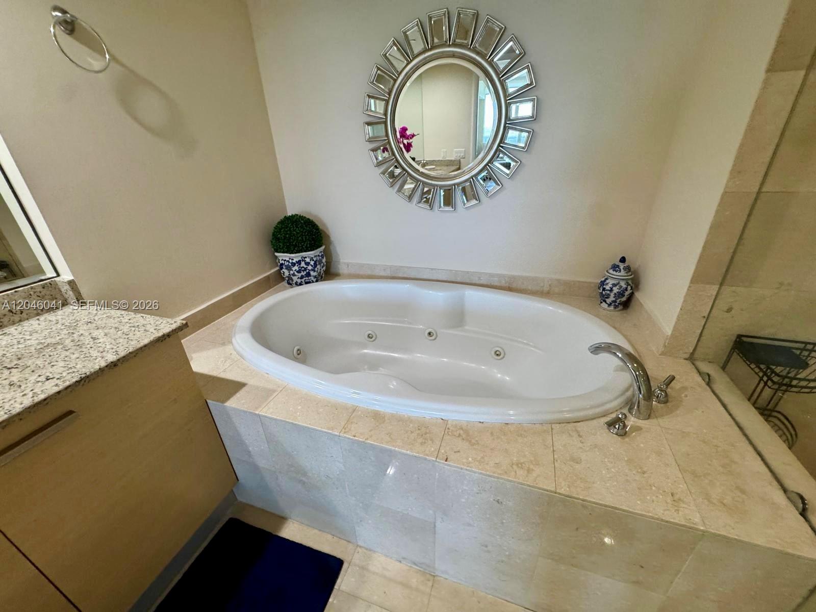 A bathroom features a jetted tub set in a beige tile surround with a mirror — 1830 S Ocean Dr # 4806, Hallandale Beach FL 33009, HALLANDALE BEACH, FL