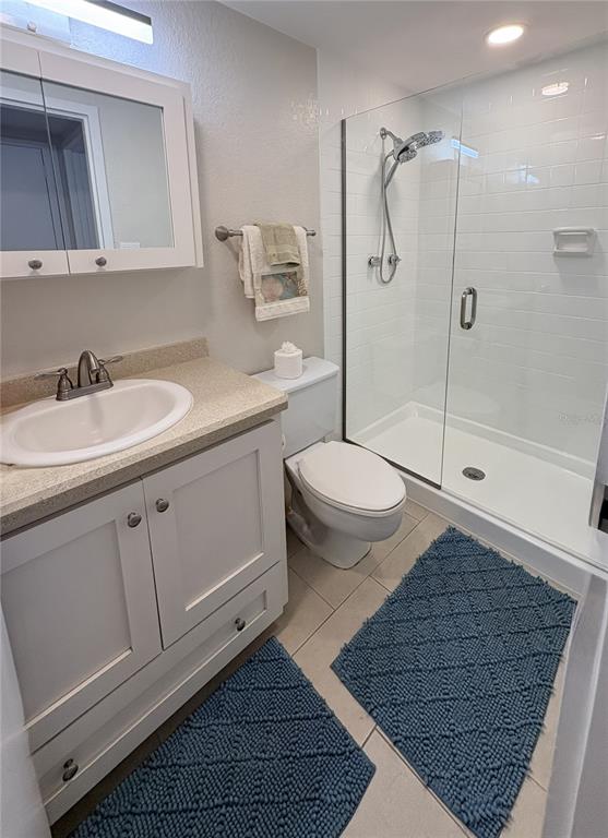 A bathroom features a white vanity, a toilet, and a glass-enclosed walk-in shower — 601 N ATLANTIC AVENUE UNIT 4080, NEW SMYRNA BEACH, FL