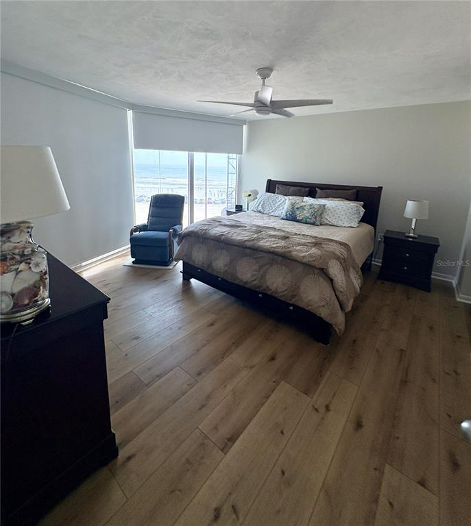 A bedroom features a bed, a blue armchair, and a view of the ocean — 601 N ATLANTIC AVENUE UNIT 4080, NEW SMYRNA BEACH, FL