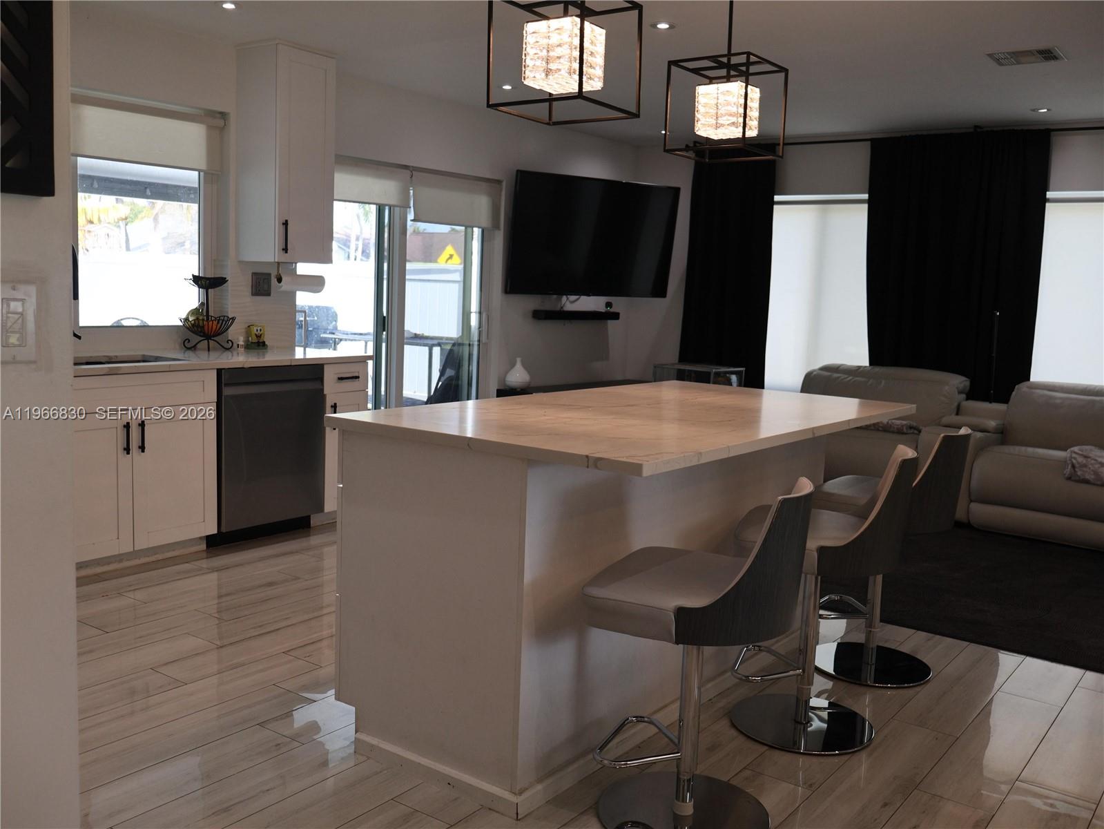 A modern kitchen features a white island with bar stools, stainless appliances, and tile flooring — 5505 SW 9th St # 0, Margate FL 33068, MARGATE, FL