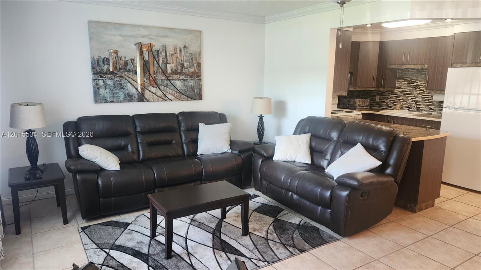 A living room features dark leather sofas, a coffee table, and an adjacent open kitchen — 226 Markham K # 226, Deerfield Beach FL 33442, DEERFIELD BEACH, FL