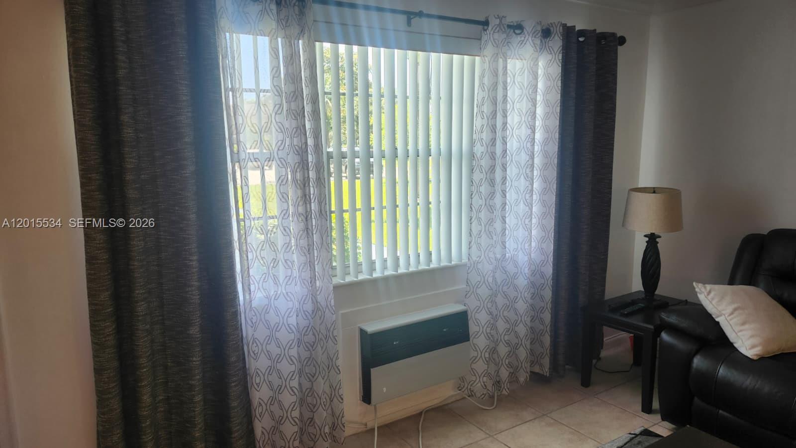 A living room features a window with vertical blinds, layered curtains, and a wall-mounted air conditioner — 226 Markham K # 226, Deerfield Beach FL 33442, DEERFIELD BEACH, FL