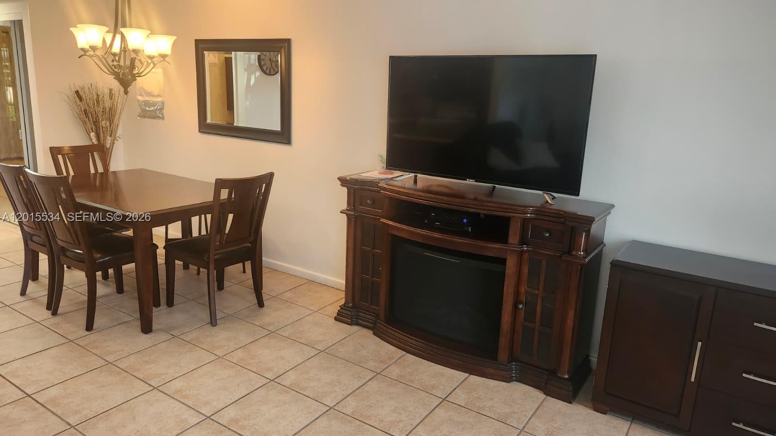 A dining area with a wooden table and chairs sits next to a media console — 226 Markham K # 226, Deerfield Beach FL 33442, DEERFIELD BEACH, FL