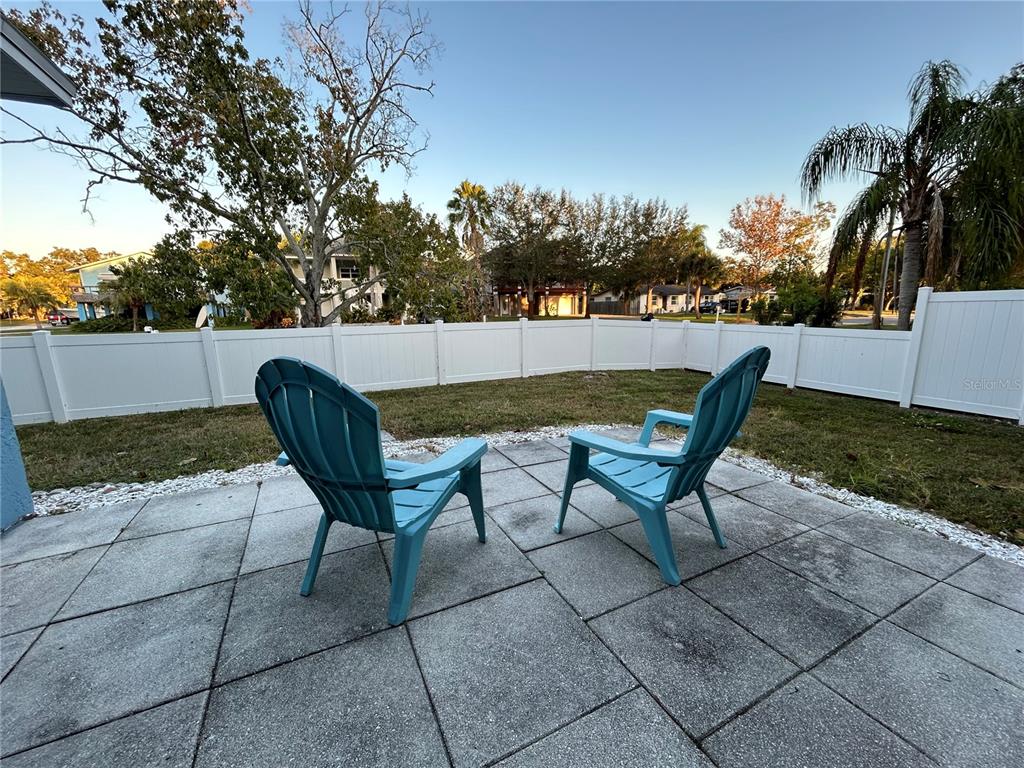 Two blue Adirondack chairs sit on a concrete patio in a fenced backyard — 5702 27TH AVENUE S, GULFPORT, FL