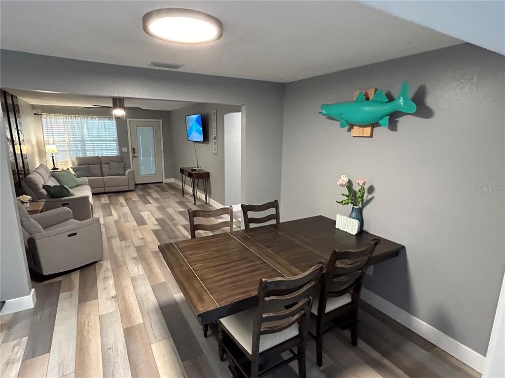 A dining area with a wooden table and chairs opens into a living room — 5702 27TH AVENUE S, GULFPORT, FL