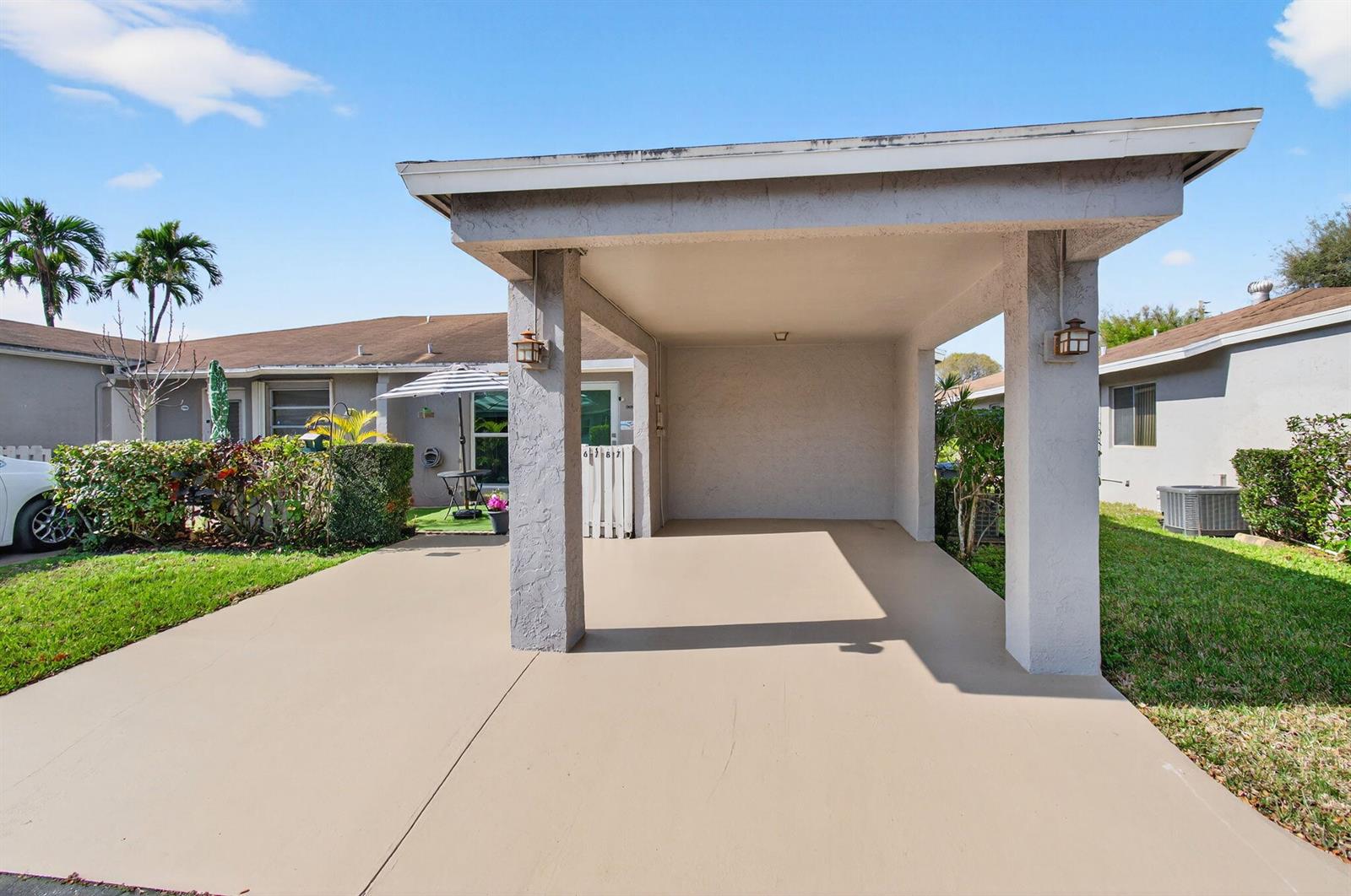 A concrete carport with two support pillars stands in front of a residential building — 6787 Moonlit Drive, Delray Beach FL 33446, DELRAY BEACH, FL