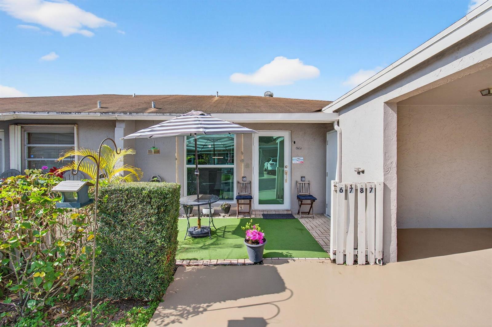 A patio area features artificial turf, a striped umbrella, and a small table with chairs — 6787 Moonlit Drive, Delray Beach FL 33446, DELRAY BEACH, FL