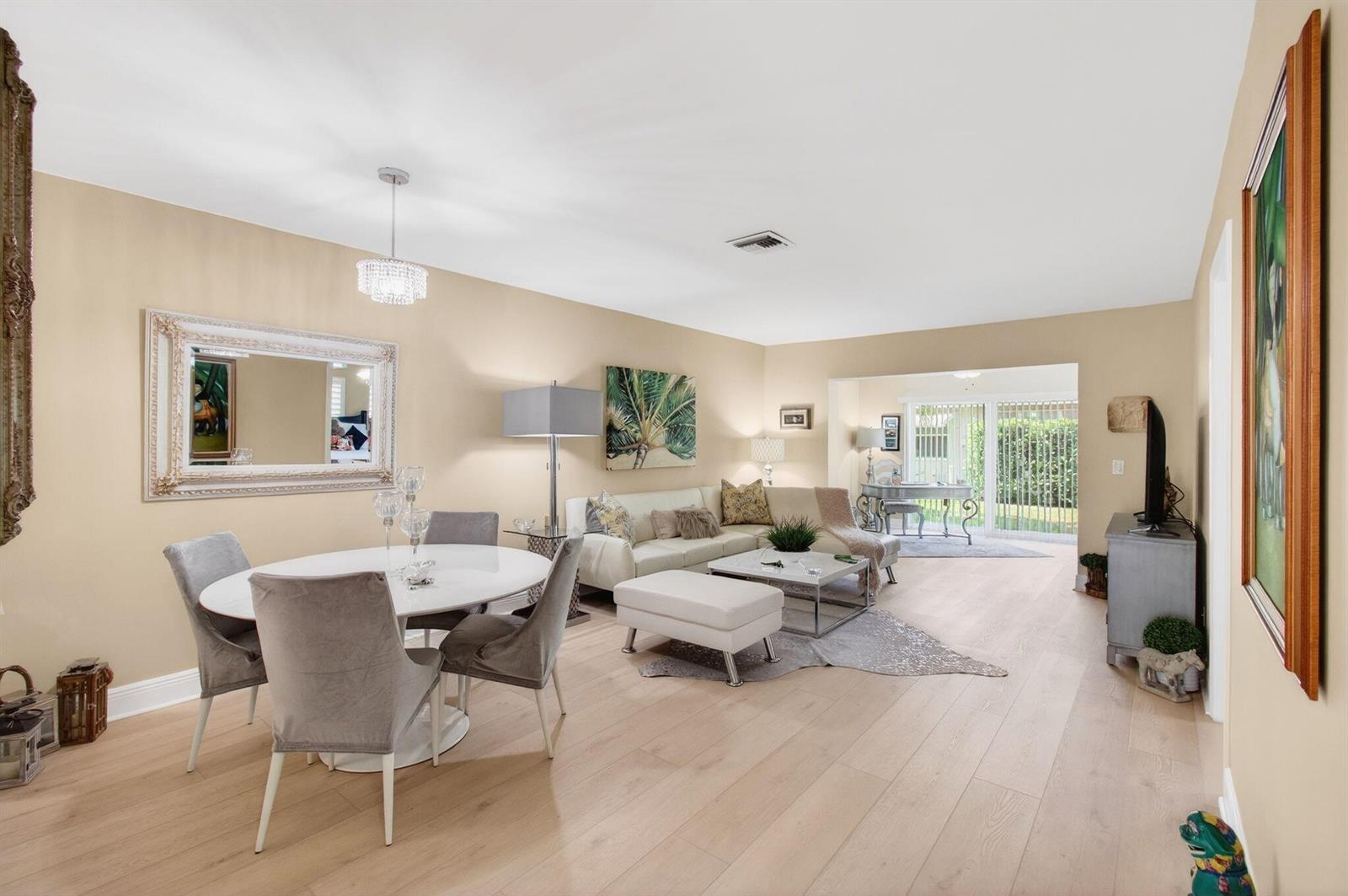 A living and dining area with light wood floors, neutral walls, and a sliding glass door — 6787 Moonlit Drive, Delray Beach FL 33446, DELRAY BEACH, FL