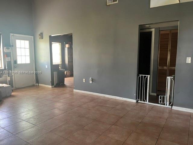 A room with tiled floors, gray walls, a white door, and a doorway with a gate — 5900 Bamboo Dr, Fort Pierce FL 34982, FORT PIERCE, FL