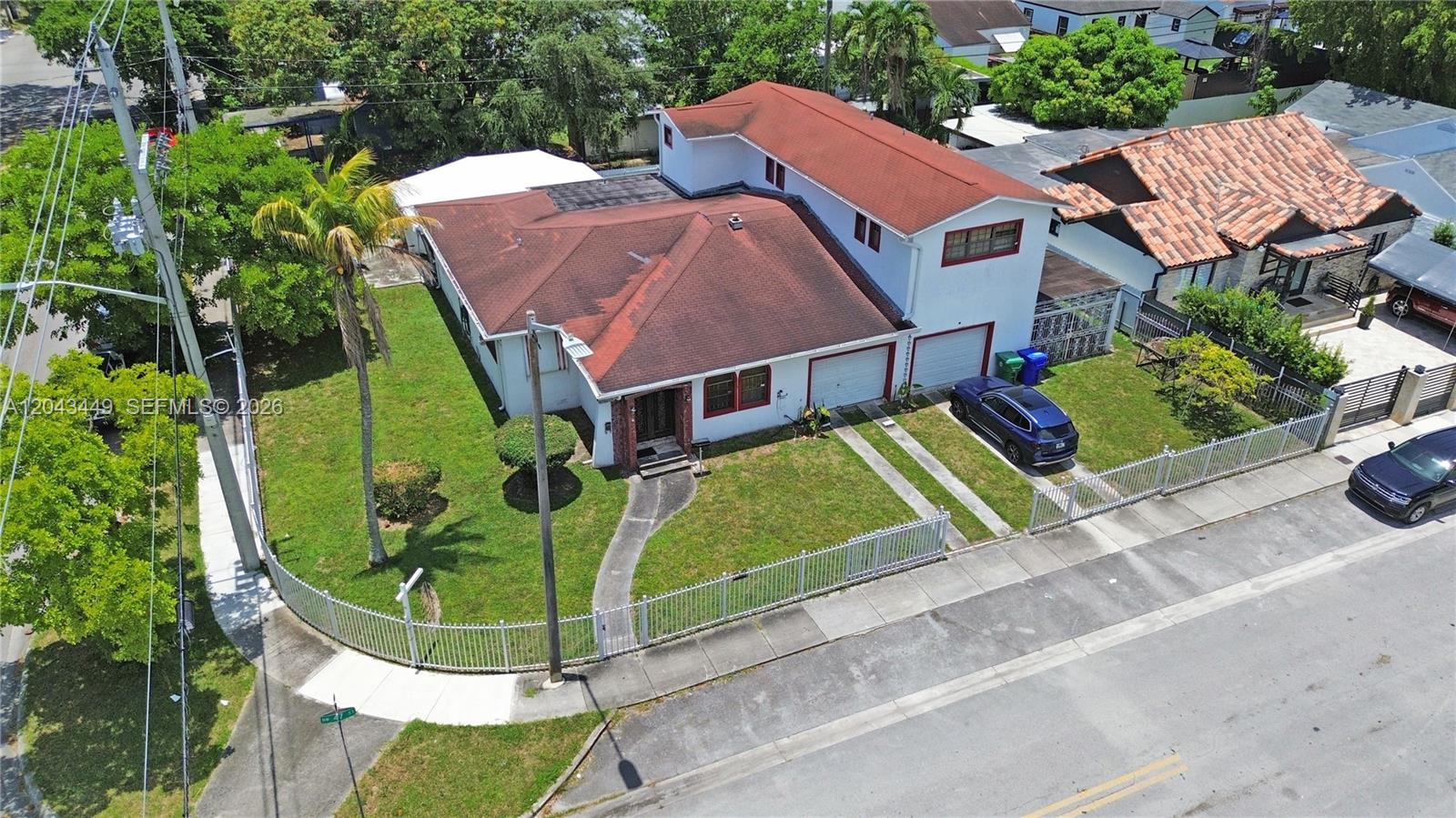 An aerial view shows a two-story house with a red roof and a fenced yard — 1000 NW 47th St, Miami FL 33127, MIAMI, FL