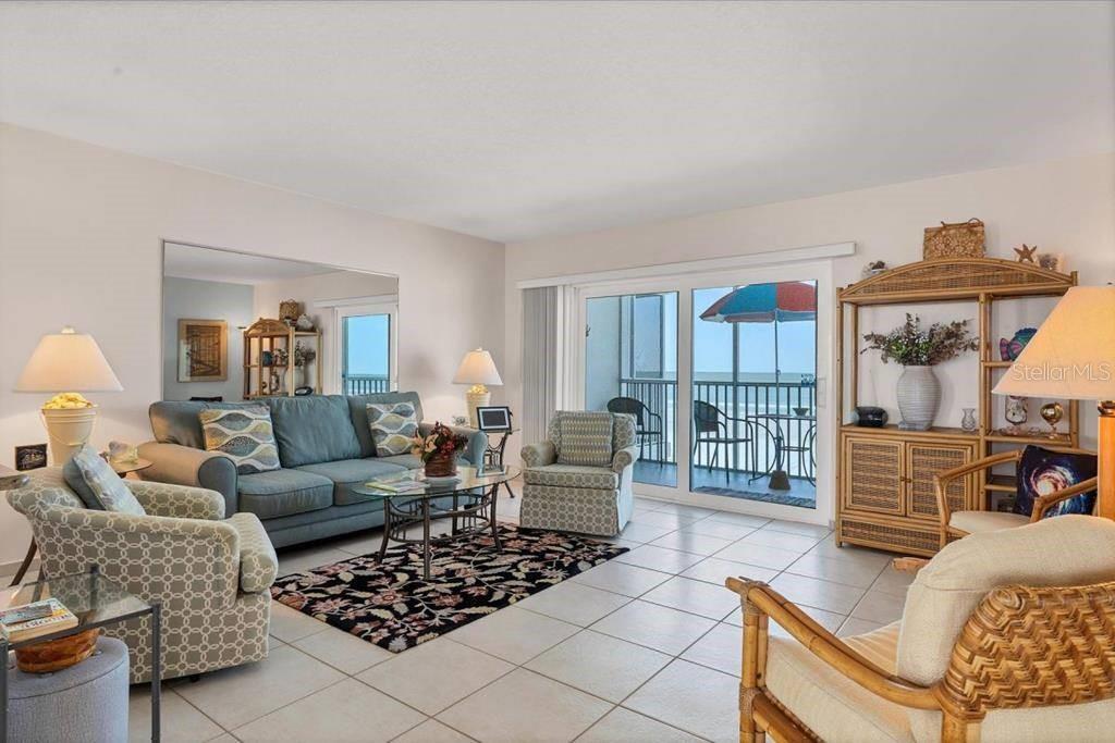 A living room features tile floors, a blue sofa, patterned armchairs, and a sliding glass door — 6154 MIDNIGHT PASS ROAD UNIT 305, SARASOTA, FL
