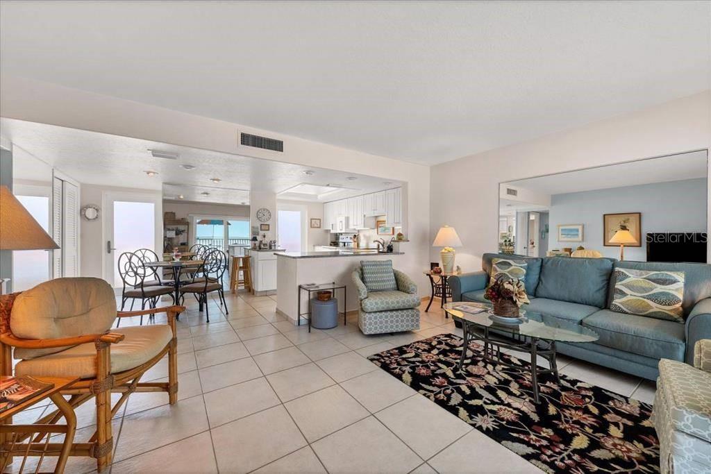 An open-concept living and dining area features tile flooring, a blue sofa, and kitchen access — 6154 MIDNIGHT PASS ROAD UNIT 305, SARASOTA, FL