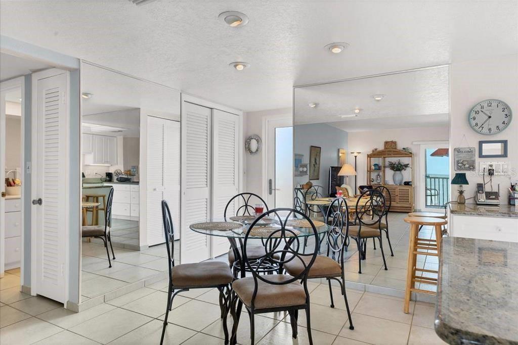 A dining area features a glass-topped table, metal chairs, tiled floors, and large wall mirrors — 6154 MIDNIGHT PASS ROAD UNIT 305, SARASOTA, FL