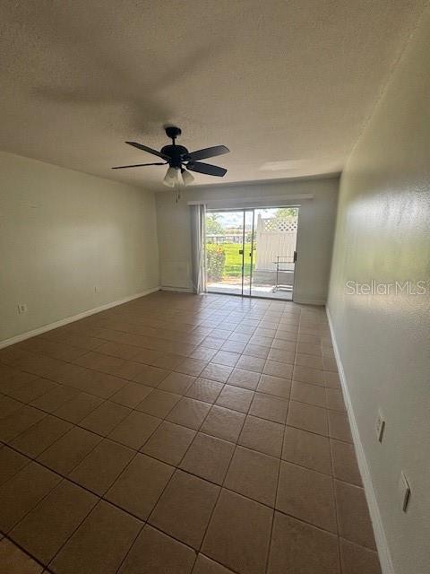 An empty room features beige tile flooring, a ceiling fan, and sliding glass doors to outside — 1695 LEE ROAD UNIT B108, WINTER PARK, FL