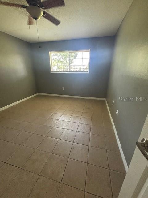 An empty bedroom features gray walls, a tiled floor, and a ceiling fan — 1695 LEE ROAD UNIT B108, WINTER PARK, FL