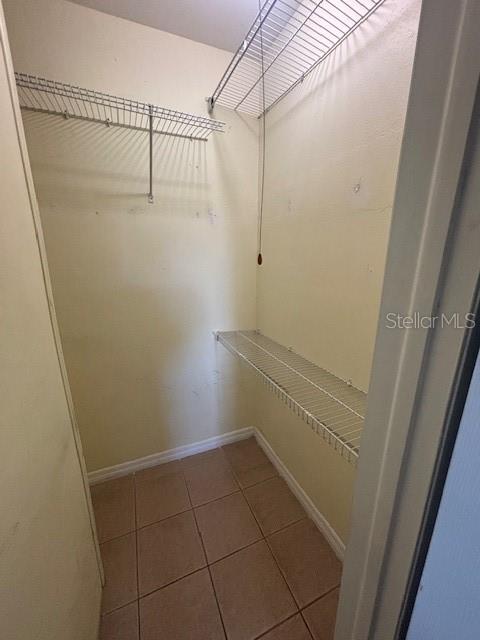 A small walk-in closet features beige walls, tile flooring, and white wire shelving — 1695 LEE ROAD UNIT B108, WINTER PARK, FL