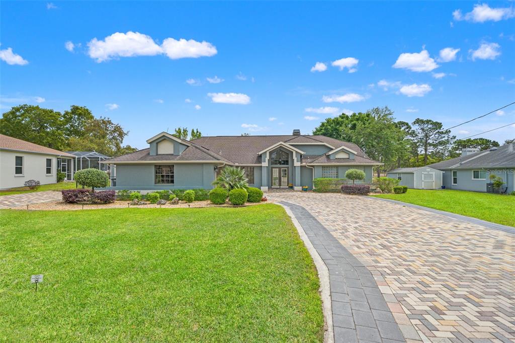 A single-story house with a gray exterior, a paved driveway, and a manicured front lawn — 5052 FLORENTINE COURT, SPRING HILL, FL