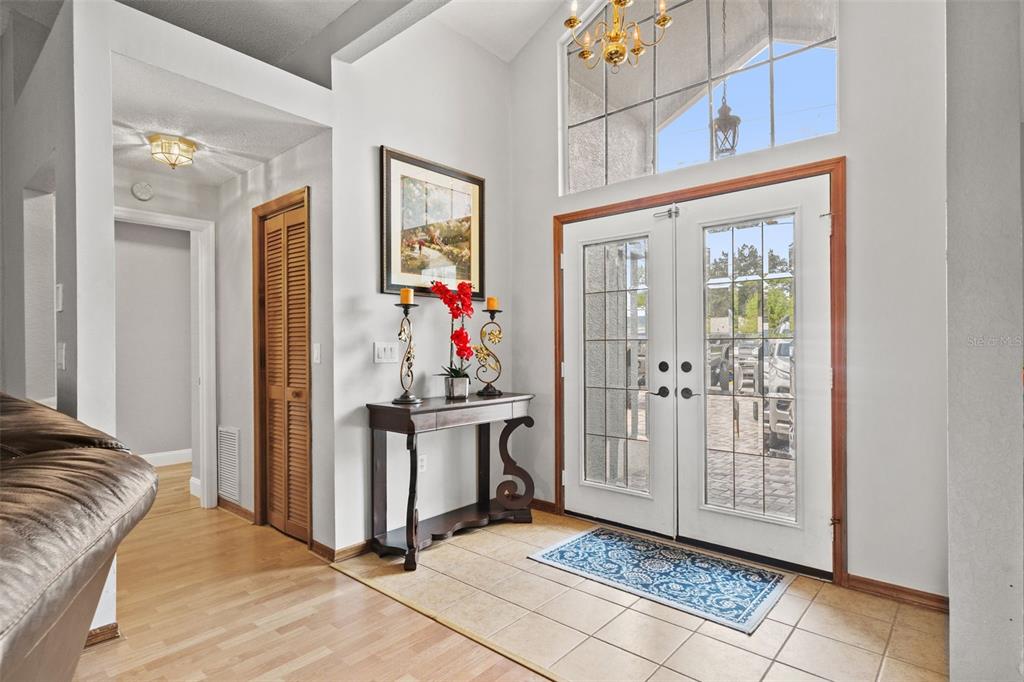 A bright entryway features double glass doors, tile flooring, a console table, and high ceilings — 5052 FLORENTINE COURT, SPRING HILL, FL