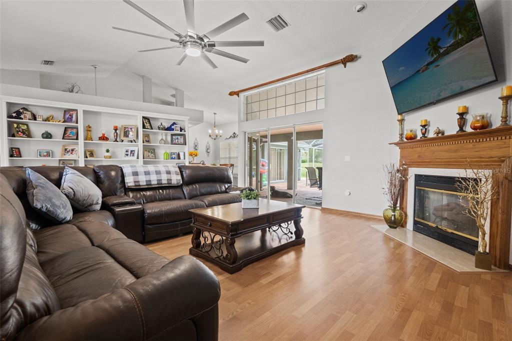 A living room features a brown leather sectional, a fireplace, and a large built-in bookshelf — 5052 FLORENTINE COURT, SPRING HILL, FL