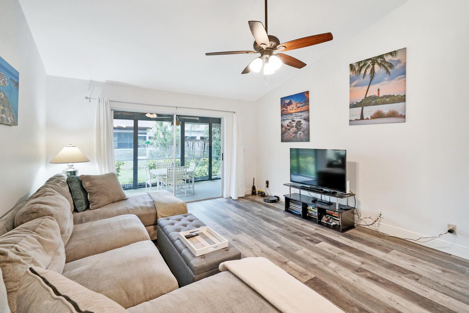 A living room features a sectional sofa, a television on a stand, and sliding doors — 113 Pinewood Court, Jupiter FL 33458, JUPITER, FL