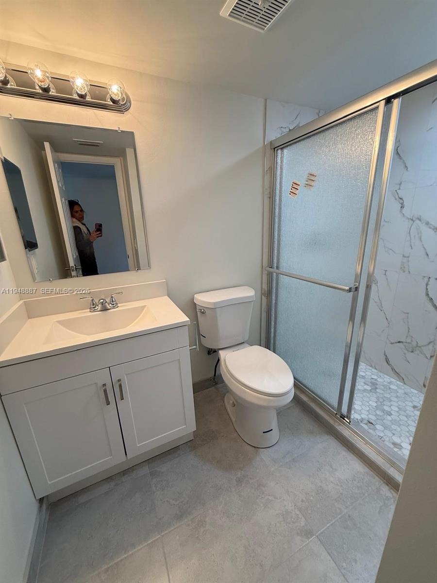 A bathroom features a white vanity, a toilet, and a glass-enclosed shower with marble tile — 7200 NW 4th Pl # 201, Margate FL 33063, MARGATE, FL