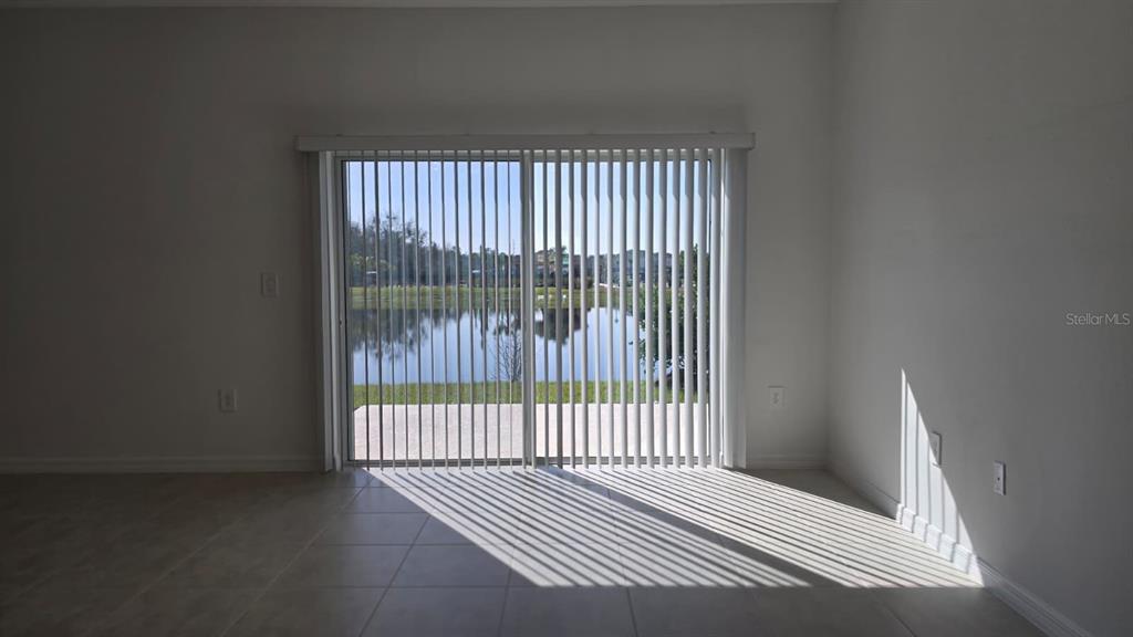 An empty room with tile flooring and vertical blinds covering a sliding glass door — 2220 PORTRAIT STREET, POINCIANA, FL