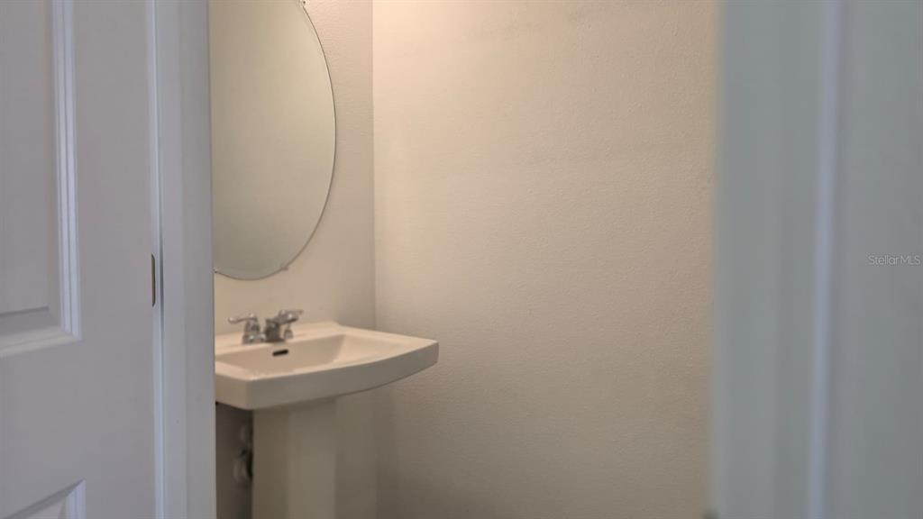 A small bathroom features a white pedestal sink and an oval wall mirror — 2220 PORTRAIT STREET, POINCIANA, FL