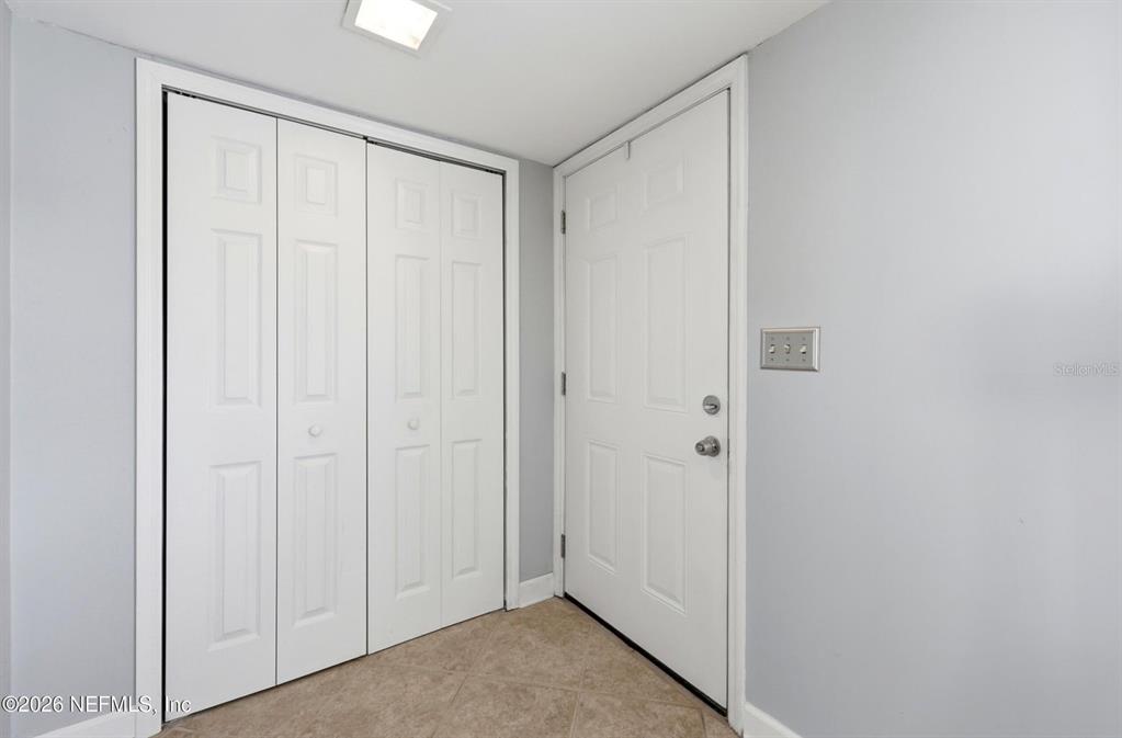 A small entryway features a white closet with bifold doors and a white entry door — 8153 SUTTON PLACE N, JACKSONVILLE, FL