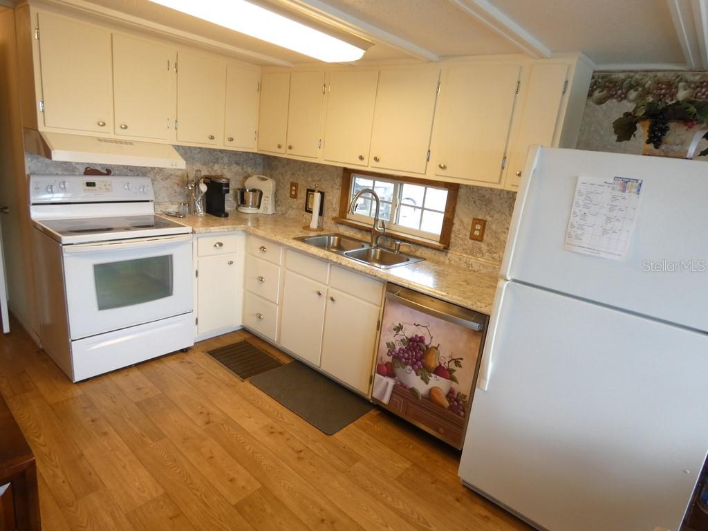 A kitchen with white cabinets, white appliances, wood-look flooring, and a patterned dishwasher panel — 12674 SEMINOLE BOULEVARD UNIT S8, LARGO, FL