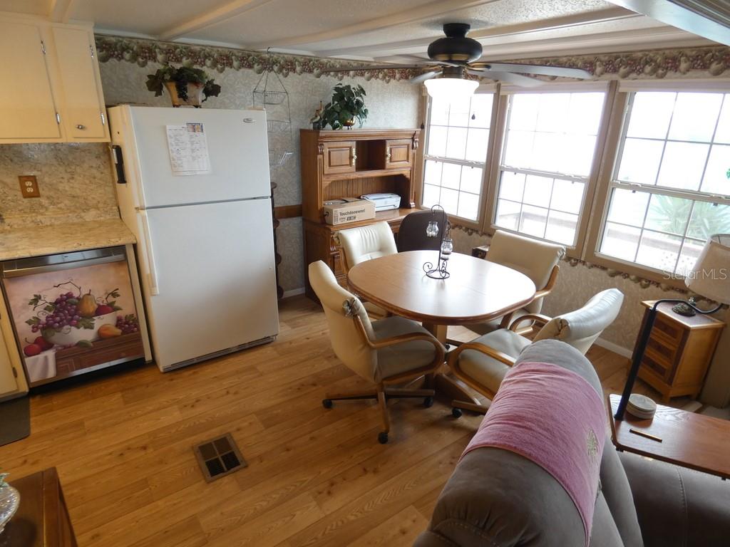 A kitchen and dining area with light wood flooring, white appliances, and a round table — 12674 SEMINOLE BOULEVARD UNIT S8, LARGO, FL