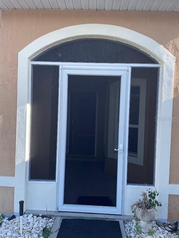 A white storm door with a screen sits within an arched entryway on a house — 4258 ORCHID BOULEVARD, LAKE WALES, FL